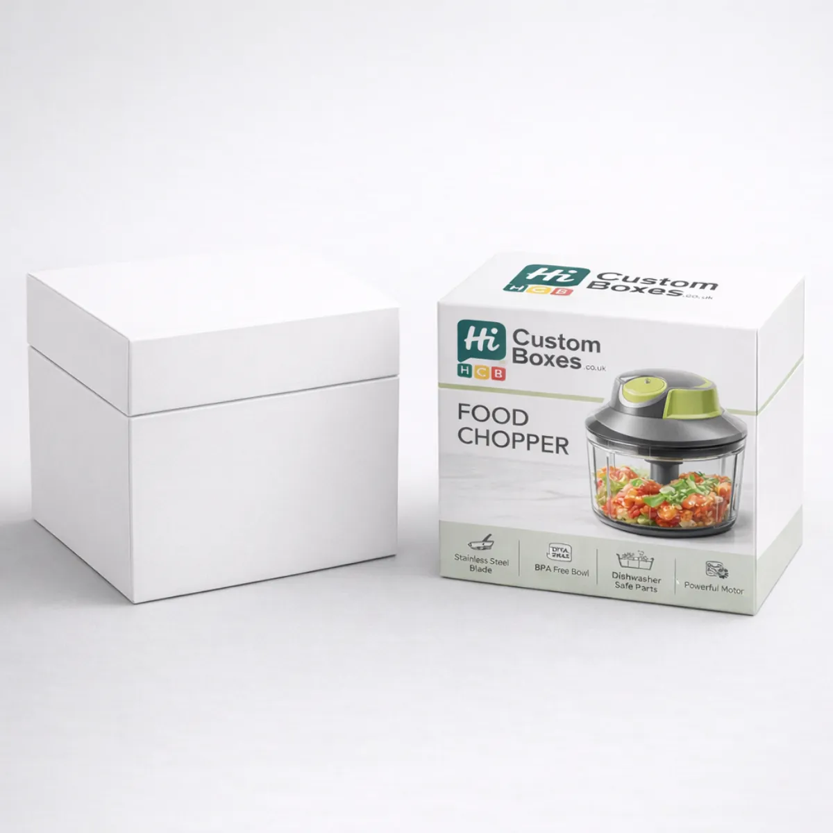 A square white gift box positioned beside a branded retail box for a green food chopper. class=